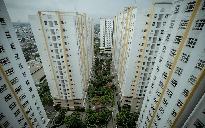 Condomínio com várias torres brancas e amarelas e um jardim entre elas