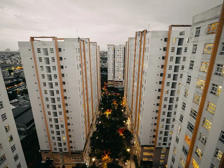 Torres de condomínio ao anoitecer, com as janelas acesas e uma árvore de Natal no centro