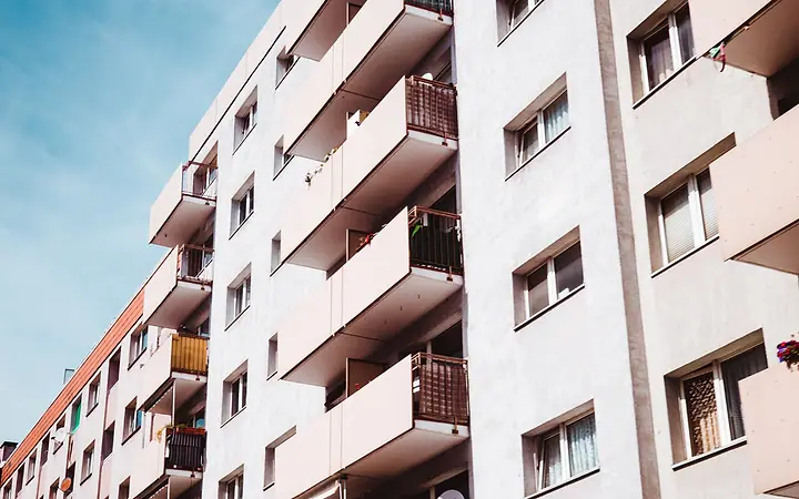 Fachada de prédio residencial branco com varandas, vista de baixo